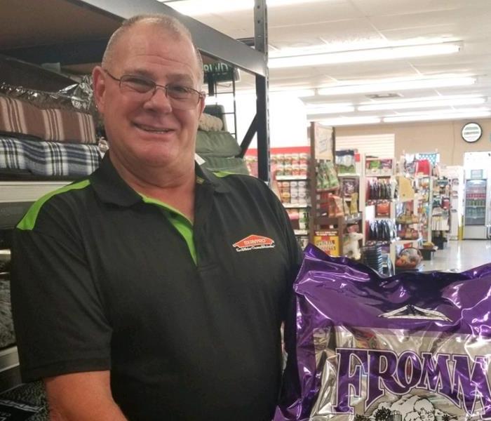 A male SERVPRO employee holding a purple bag of dog food. 