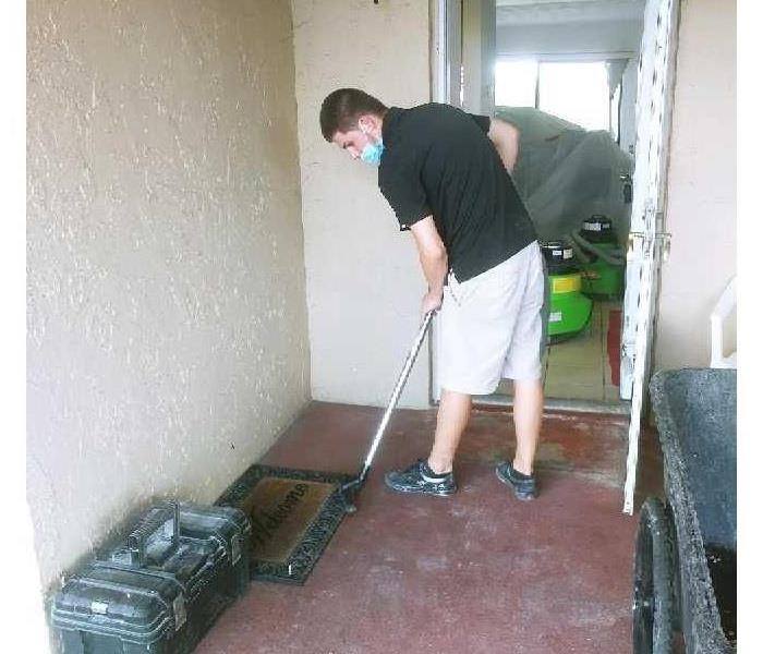 SERVPRO technician with water removal equipment on the front porch of a home