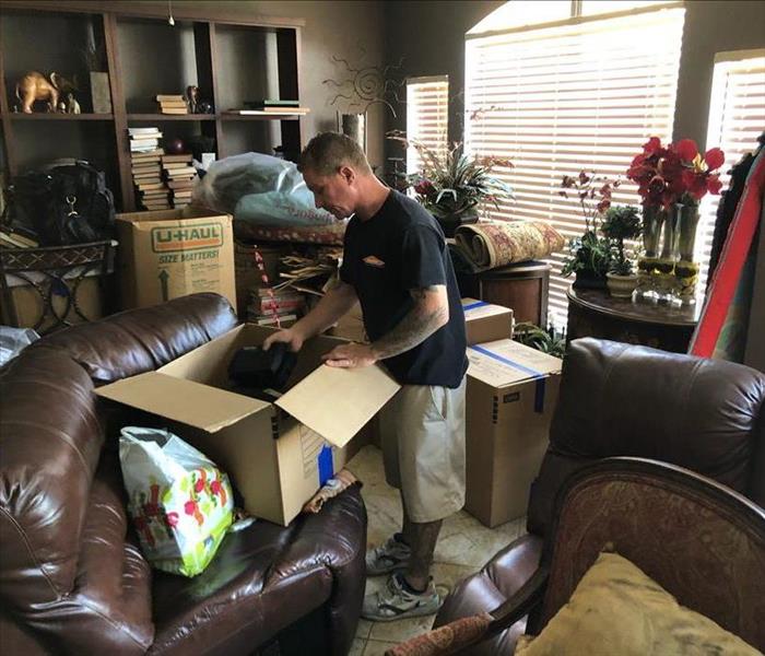 SERVPRO tech in furnished living room with packing boxes 