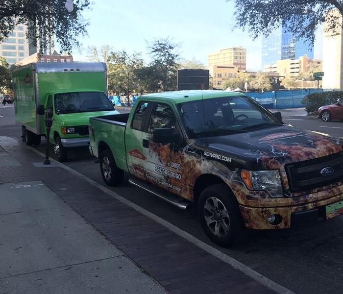 Two SERVPRO vehicles parked on a sidewalk. 