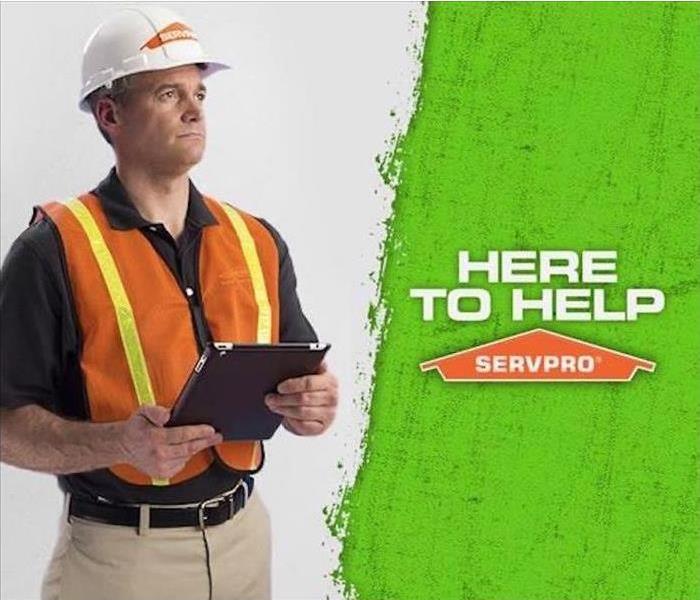 SERVPRO tech holding an iPad with the caption Here to Help