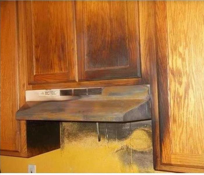 Smoke damaged kitchen vent hood, cabinets and wall